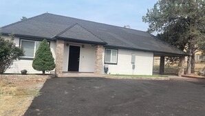 A single-story house with a dark roof, a front door, and a small porch. - Modern Haven in Klamath Falls - A Stylish Home Away from Home (Klamath Falls)