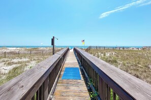 A wooden boardwalk leading to a beach with a blue mat in the center. - Charming Gulf Front Condo in the Heart of Orange Beach! 2br/2ba with Gulf Views! (Orange Beach)
