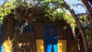 Une cour avec une structure en bois, une porte bleue et une chaise blanche.