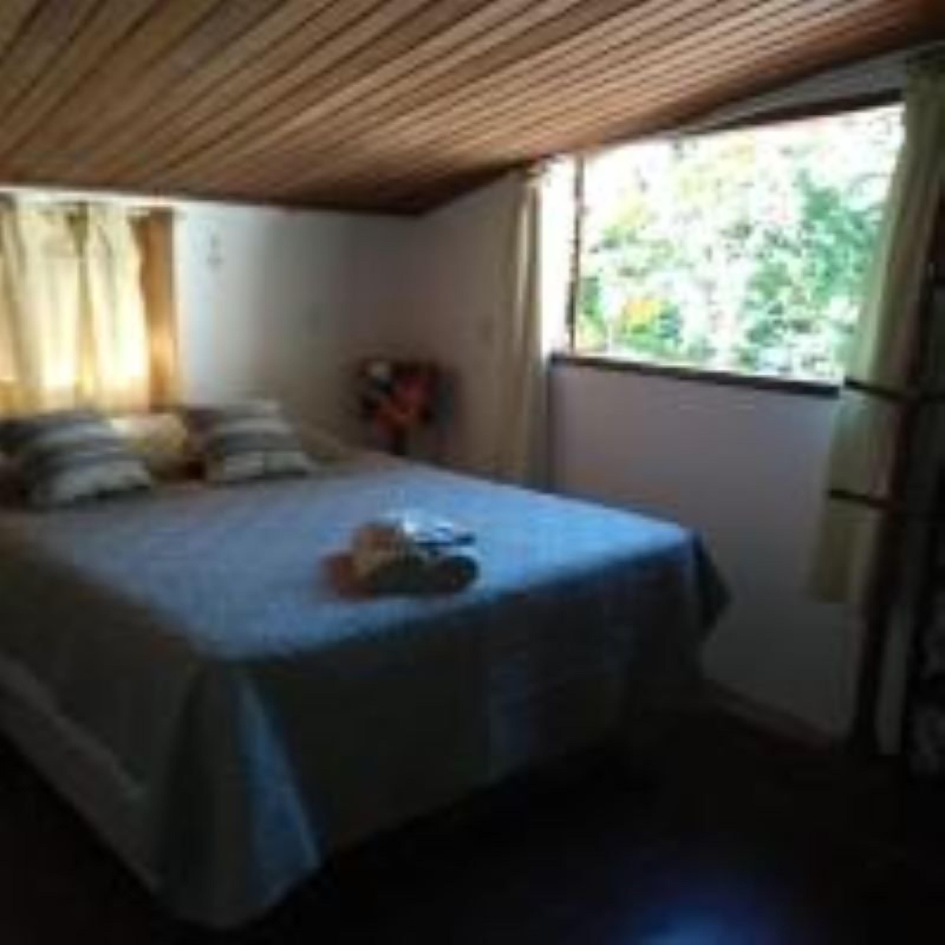 Quarto com cama, janela e teto de madeira.