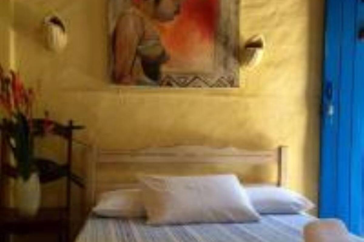 Une pièce avec un lit, un tableau au mur et une porte bleue.