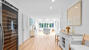 Een moderne keuken met een centraal eiland, witte kasten en uitzicht op de eethoek.