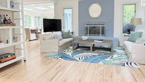 A spacious living room with a fireplace, two sofas, a coffee table, and a TV.