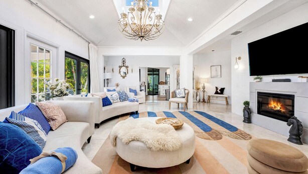 A spacious living room with a white sofa, a fluffy ottoman, and a fireplace. - Spacious Family Retreat with Pool Gym Sauna Pickleball and Guest Suite SLEEPS 16 (Naples)