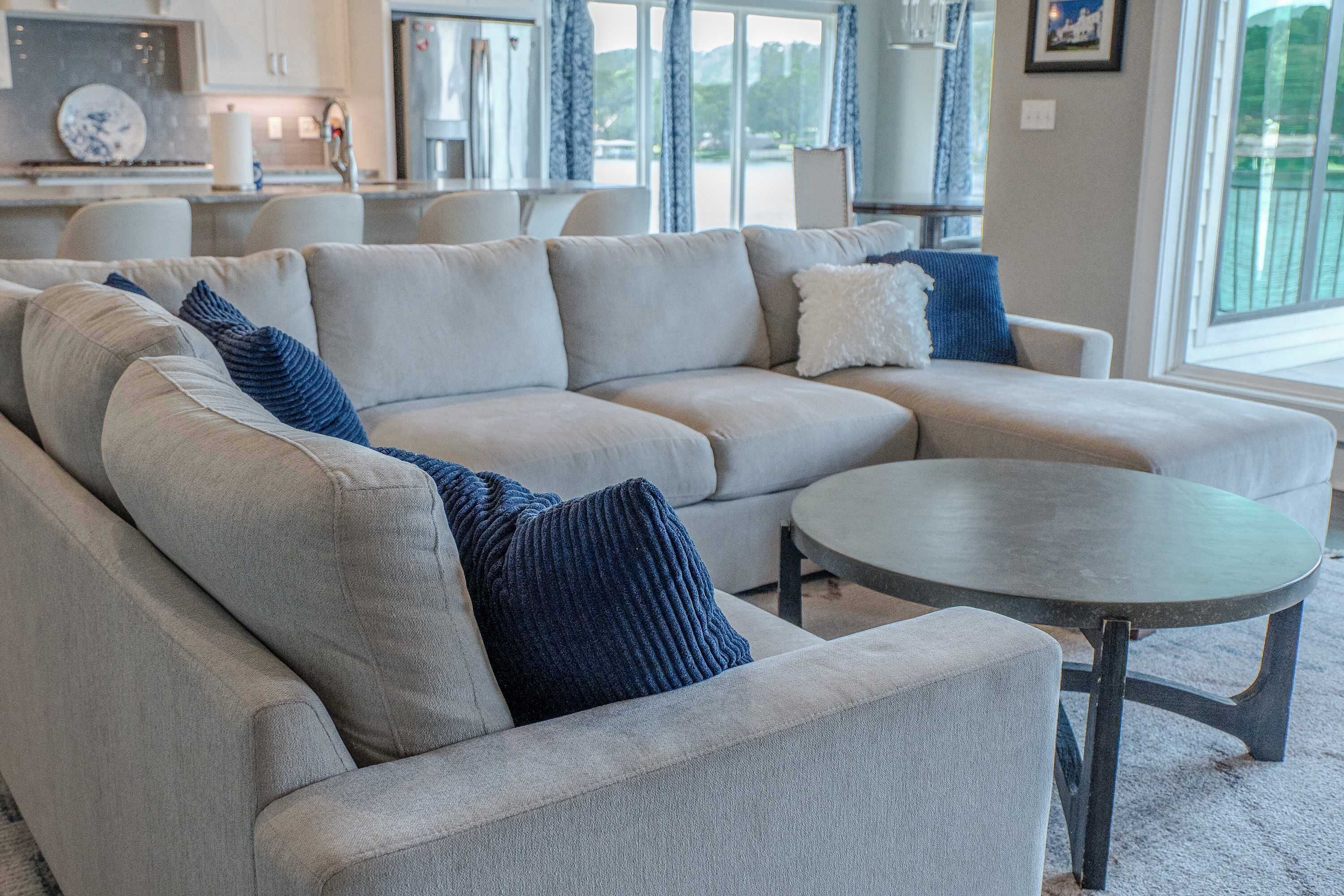A sectional sofa with a round coffee table, a dining area with chairs, and a view of the outdoors.