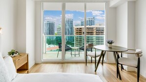 A modern hotel room with a large sliding glass door leading to a balcony with a city view. - ARYA HOTEL STUDIO OCEAN VIEW BALCONY FREE PARKING (Miami)