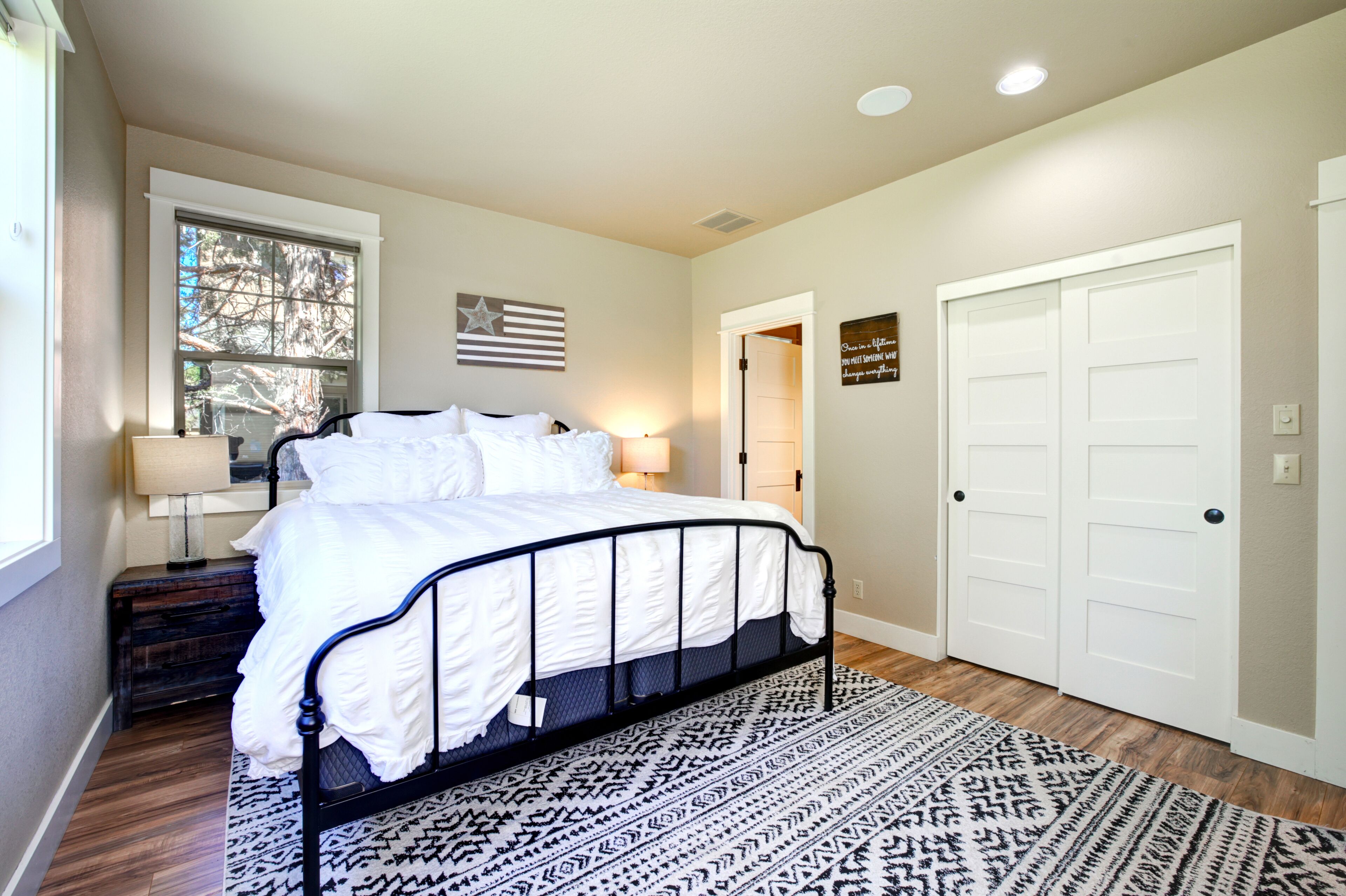 Un dormitorio con cama, ventana, puerta y alfombra.