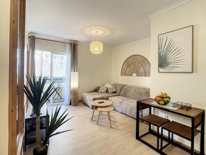 A modern living room with a sofa, a round table, and a coffee table. There is a large plant, a lamp, and a wall-mounted artwork. - Sea Mountain by Atlantic Holiday (Porto Moniz)