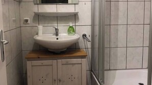 A bathroom with a sink, mirror, and shower.