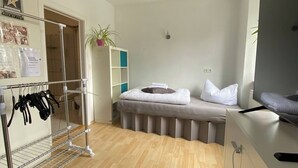 A hotel room with a bed, a bedside table, a TV, a wardrobe, and a shoe rack.