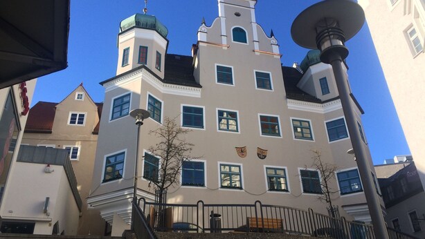 A multi-story building with a central tower, multiple windows, and a small balcony.