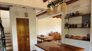 Una cocina con vigas de madera, una isla central, armarios blancos y una escalera que sube a otro nivel.