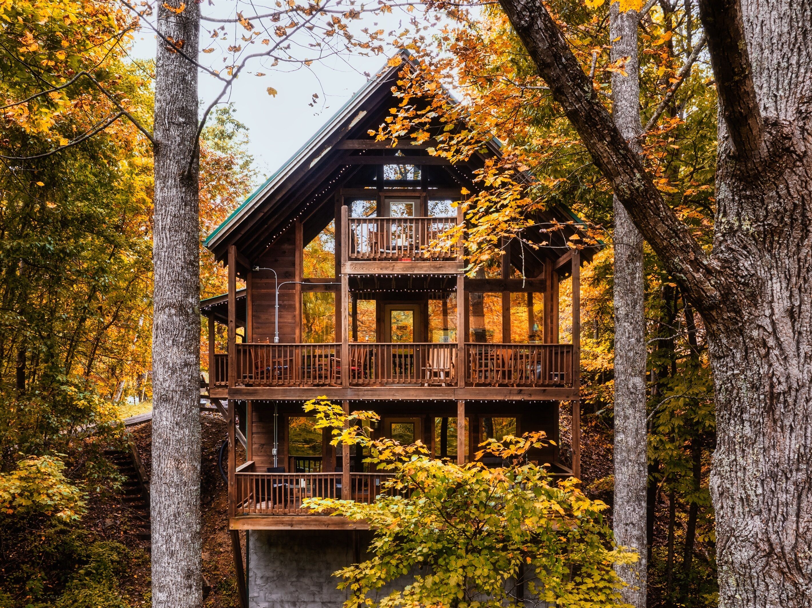 Una cabaña con fachada de madera, varios balcones y vistas al bosque circundante.