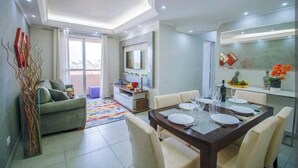 A modern dining area with a large table set for four, a sofa, a TV, and a balcony with a view. - Apartment 5 guests Santo André near AV Estado Prox Shopping (Utinga Santo André)