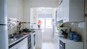 A modern kitchen with white cabinets, a stainless steel sink, and a window providing natural light. - Apartment 5 guests Santo André near AV Estado Prox Shopping (Utinga Santo André)