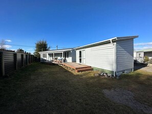 A single-story mobile home with a covered porch and a small deck.