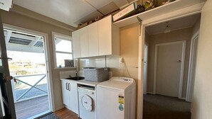 A compact kitchen with a washing machine, a sink, and a small countertop. - Bach Bliss, Twizel. Free Wifi. (Twizel)