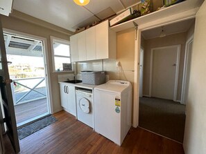 A compact kitchen with a washing machine, a sink, and a small countertop.