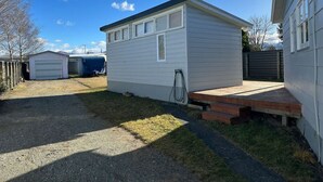 A single-story, white mobile home with a small porch and a gravel driveway. - Bach Bliss, Twizel. Free Wifi. (Twizel)