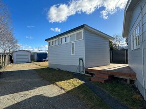 A single-story, white mobile home with a small porch and a gravel driveway.