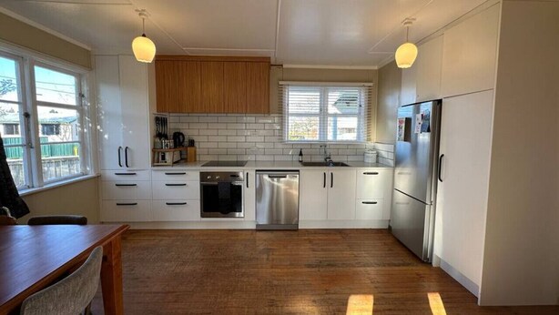 A modern kitchen with white cabinets, stainless steel appliances, and a wooden dining table. - Bach Bliss, Twizel. Free Wifi. (Twizel)