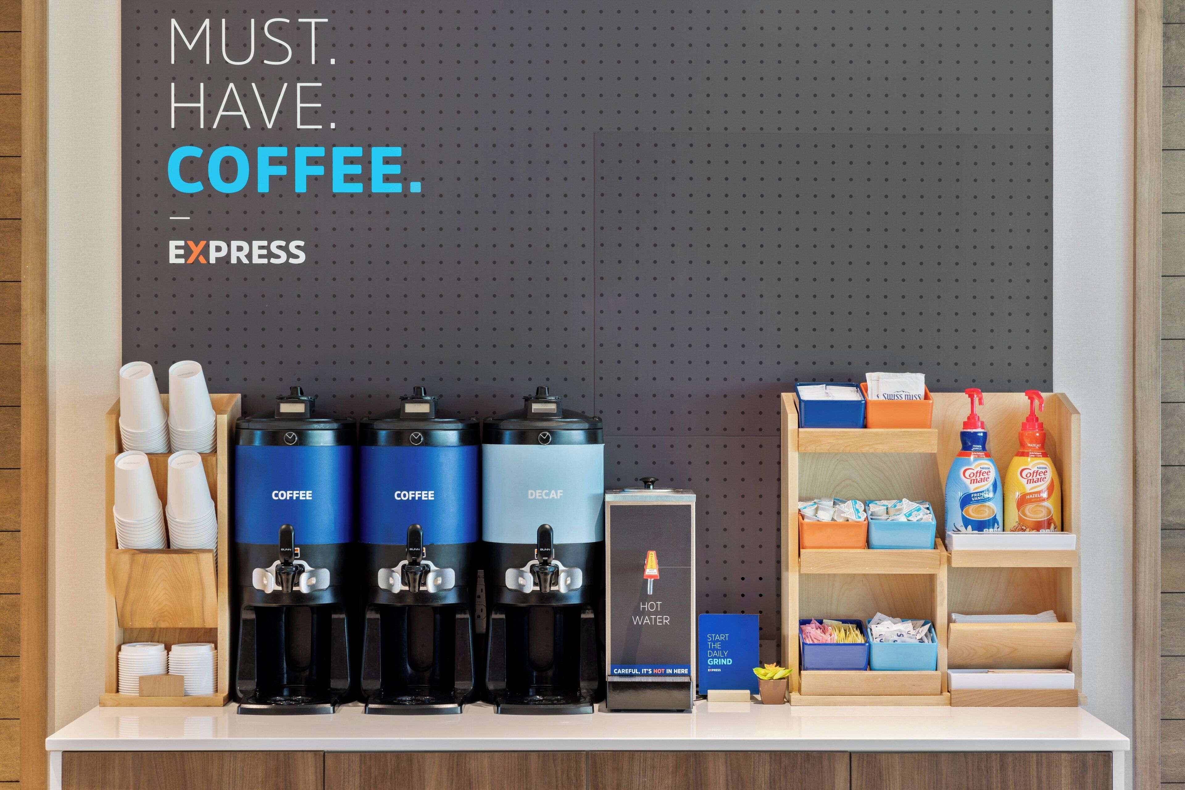 Una estación de café con tres dispensadores de café, un dispensador de agua caliente y un molinillo.