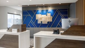 A hotel reception area with modern design, featuring a reception desk, a digital display, and a wall with geometric patterns. - Holiday Inn Express & Suites Waynesboro East by IHG (Waynesboro)