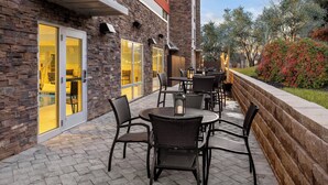 An outdoor patio with wicker furniture and a stone wall. - Holiday Inn Express & Suites Waynesboro East by IHG (Waynesboro)