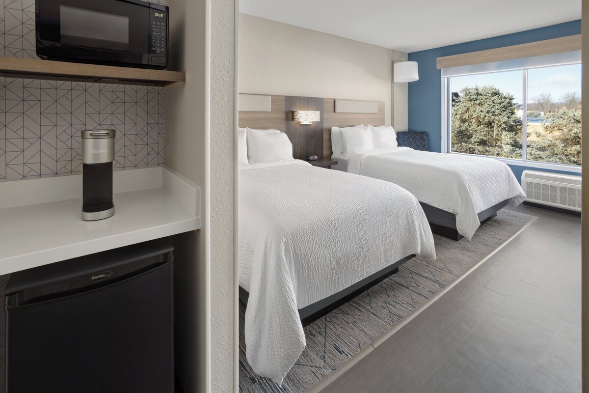 Une chambre d’hôtel avec deux lits, un four à micro-ondes, une machine à café et une vue sur les arbres.