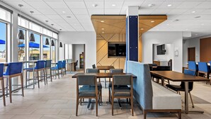 A modern dining area with high tables and chairs, large windows, and a view of the outside. - Holiday Inn Express & Suites Marinette by IHG (Marinette)