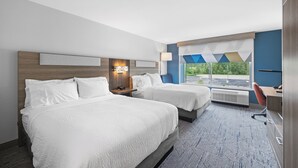 A hotel room with two beds, a desk, a chair, a window with a view, and a wall-mounted lamp. - Holiday Inn Express & Suites Marinette by IHG (Marinette)