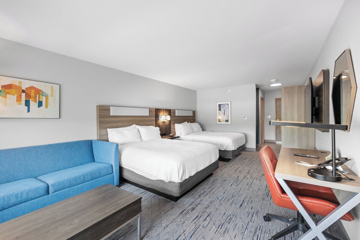 Une chambre d’hôtel avec un grand lit, un bureau avec une chaise, un canapé bleu et un téléviseur.