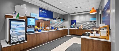 A modern breakfast area with a self-serve station, including a yogurt machine, eggs, and milk dispenser.