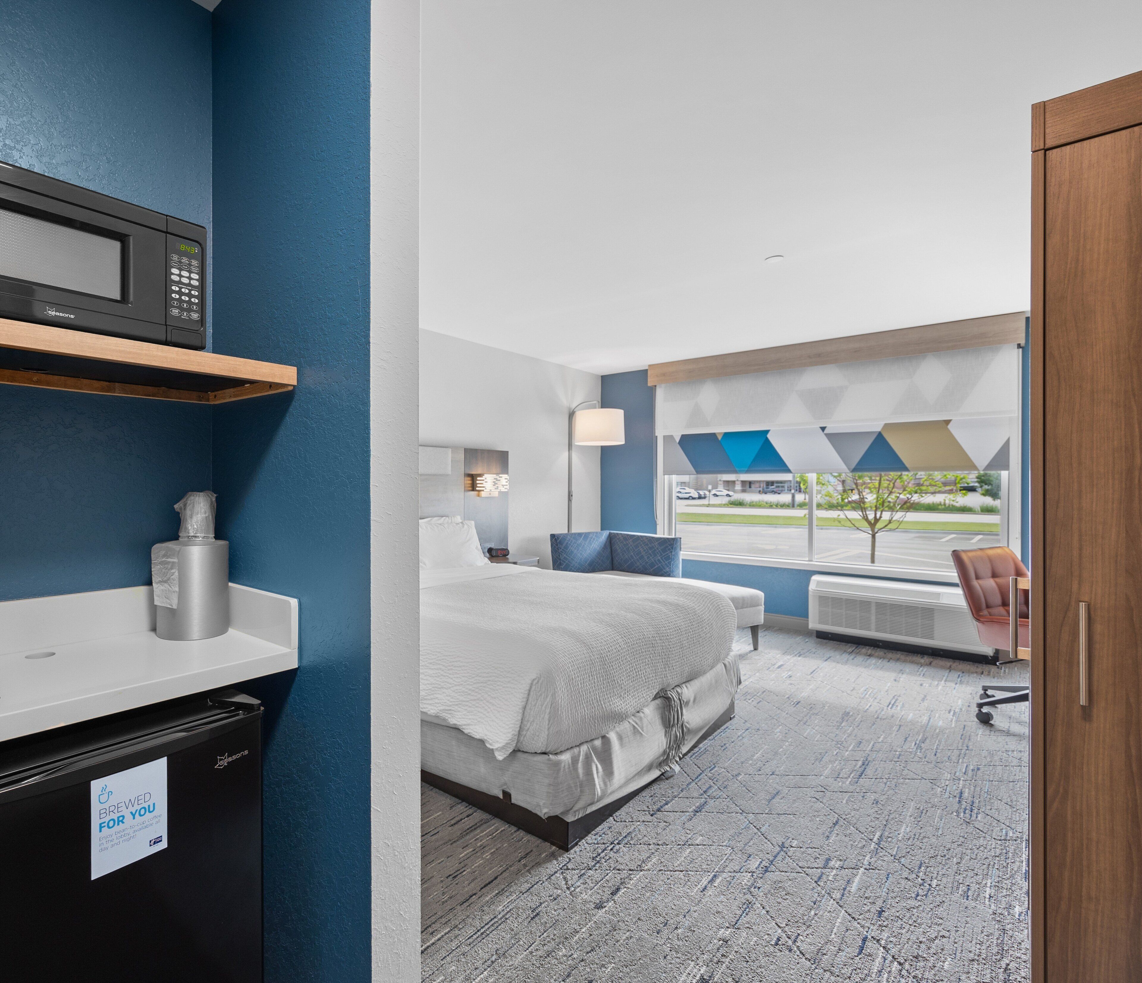 A hotel room with a bed, bedside table, and a microwave.