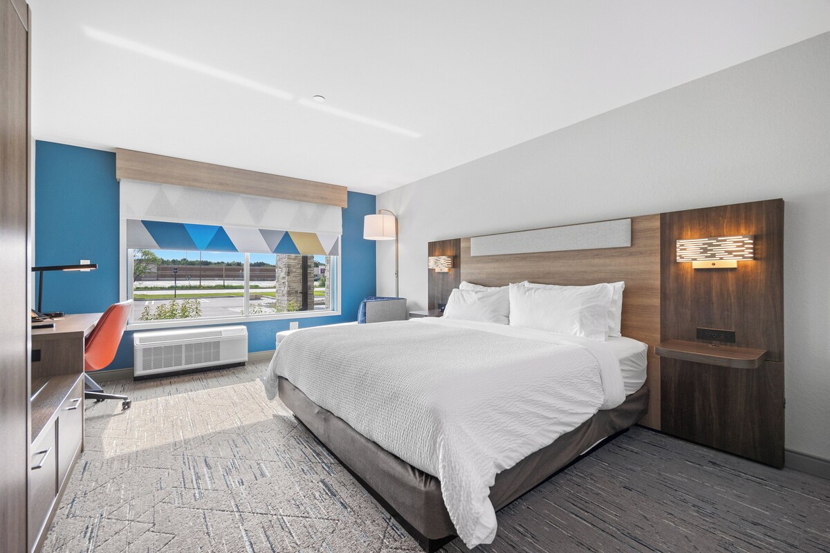 Une chambre d’hôtel moderne dotée d’un grand lit, d’un bureau et offrant une vue sur l’extérieur.