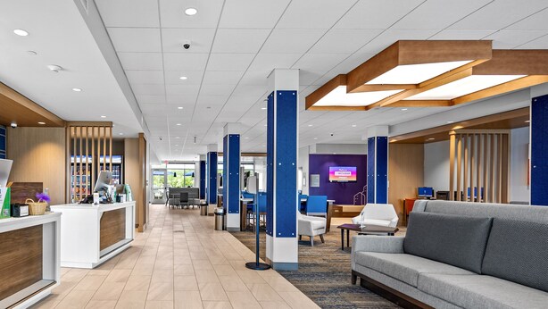 A modern hotel lobby with a reception desk, seating area, and a large screen displaying content. - Holiday Inn Express & Suites Marinette by IHG (Marinette)