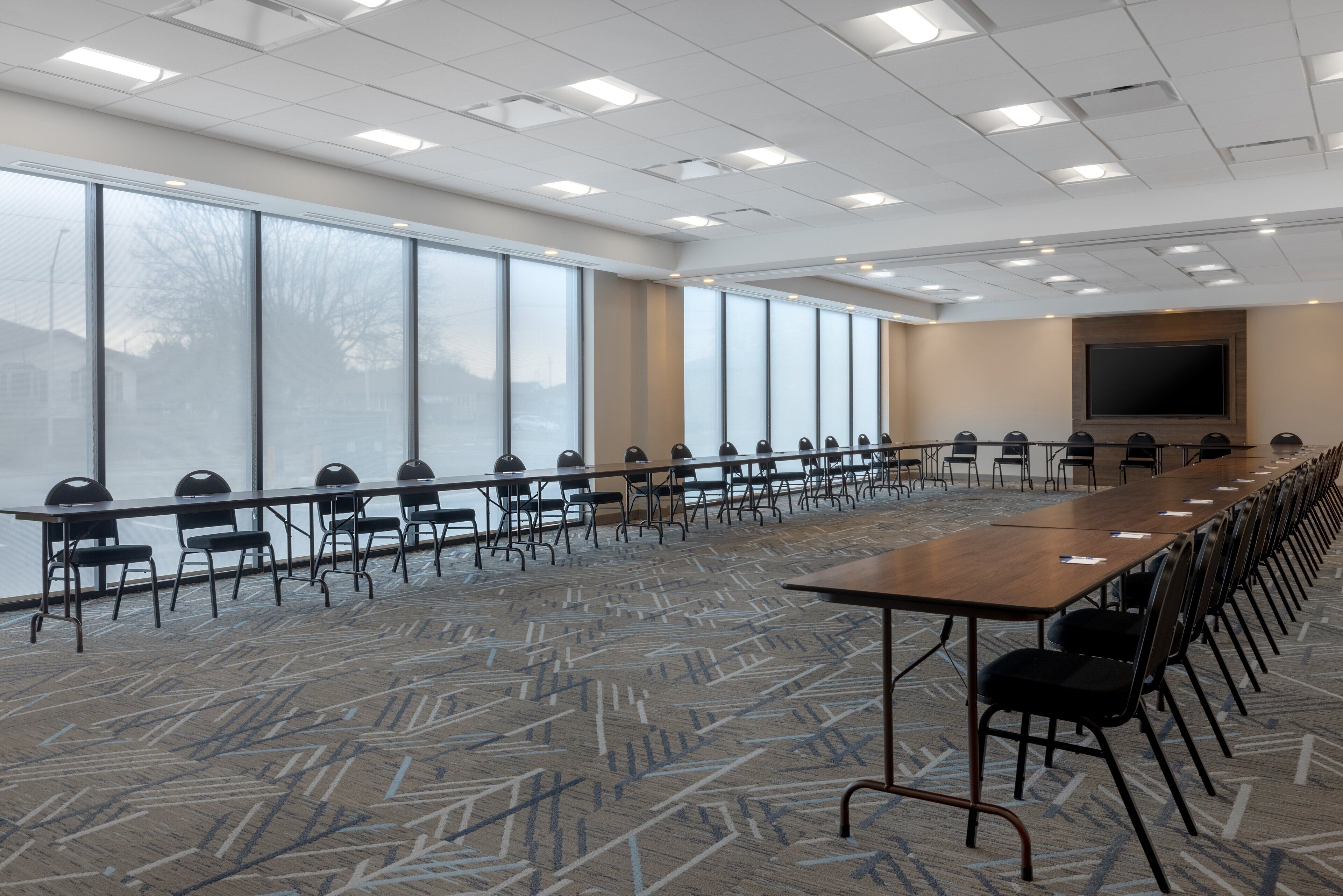 A conference room with a long table, chairs, and large windows.