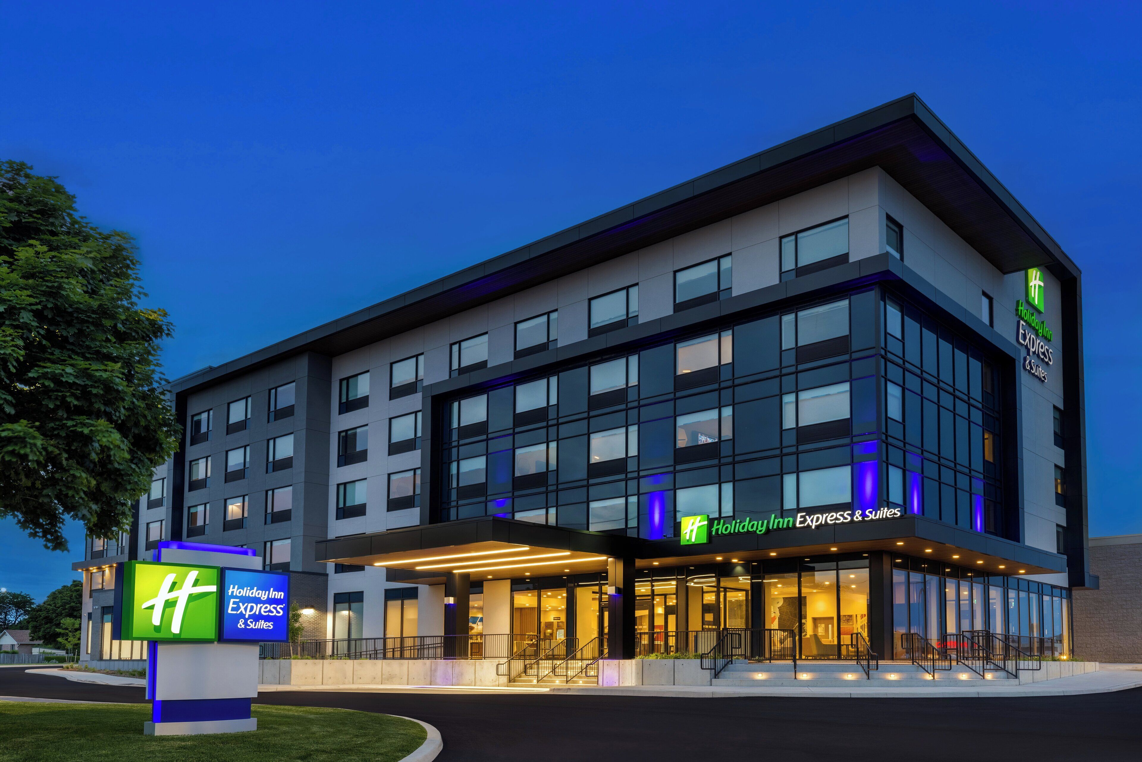 Edificio de Holiday Inn Express & Suites con un diseño moderno, ventanas amplias y una entrada bien iluminada.