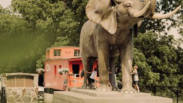 A large elephant statue on a pedestal with a small building in the background.