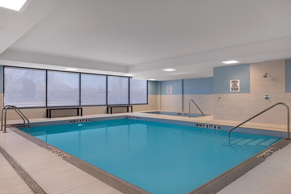 A swimming pool with clear depth markers, a sunroof, and a tiled floor.