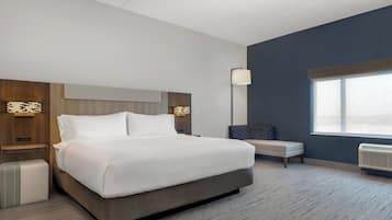 Une chambre d’hôtel moderne avec un grand lit, une banquette, une table de chevet et une fenêtre.