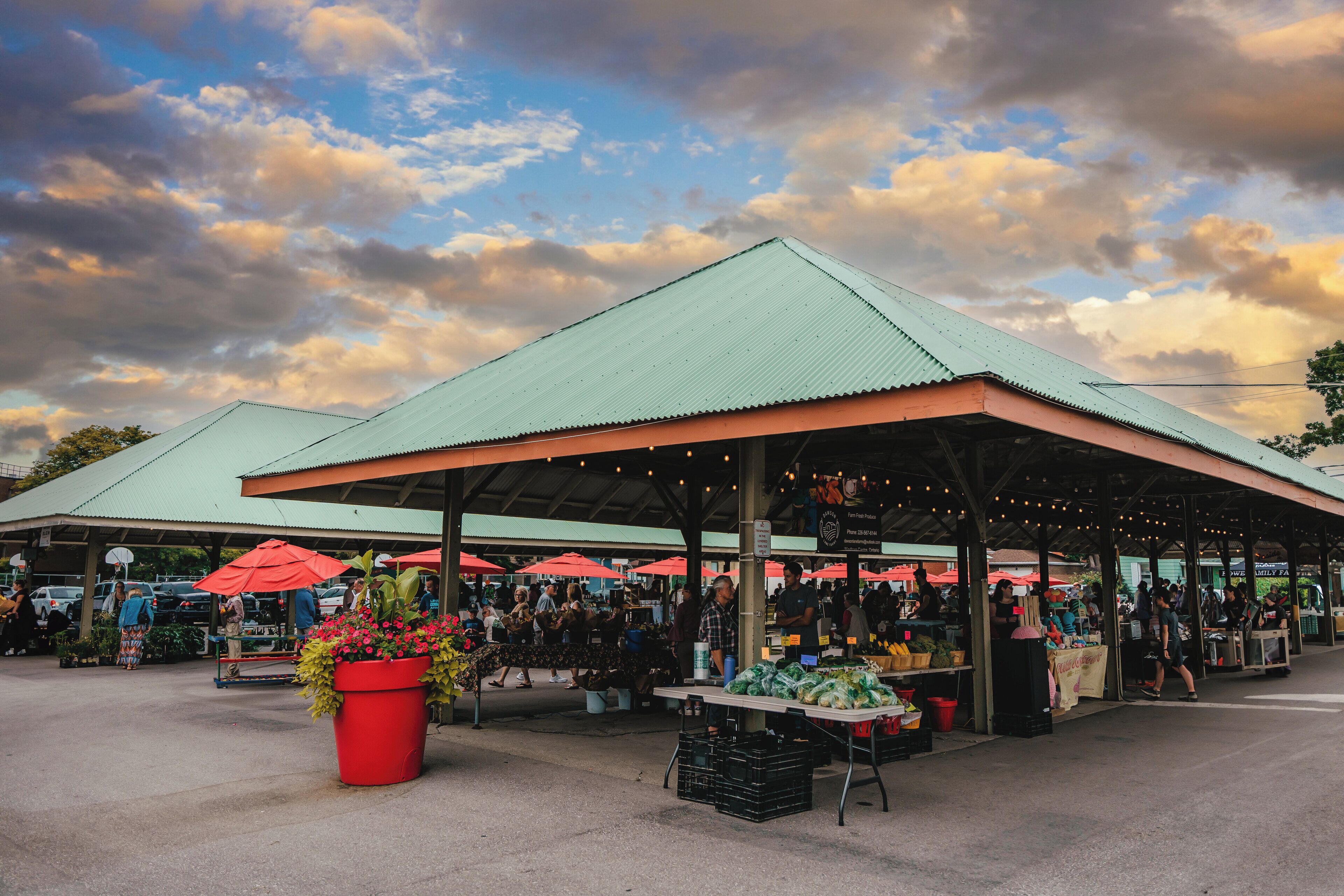 An outdoor market with covered stalls and a large central table.