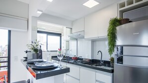 Une cuisine moderne avec des meubles blancs, un réfrigérateur en acier inoxydable et un plan de travail noir.