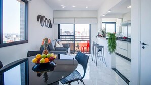 Un appartement moderne comprenant un coin repas, une cuisine et un balcon avec vue sur la ville.