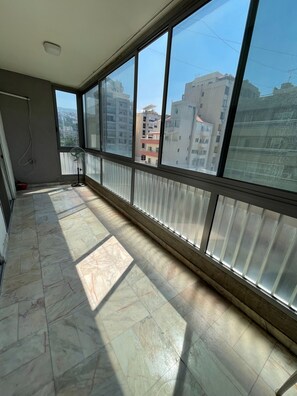 A room with a large window, tiled floor, and a ceiling vent.