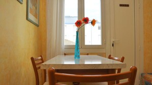 Un comedor con una mesa de mármol, sillas de madera y un jarrón con flores.