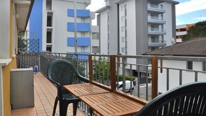 Un balcón con mesa y sillas de madera, con vistas a una zona residencial con edificios modernos.