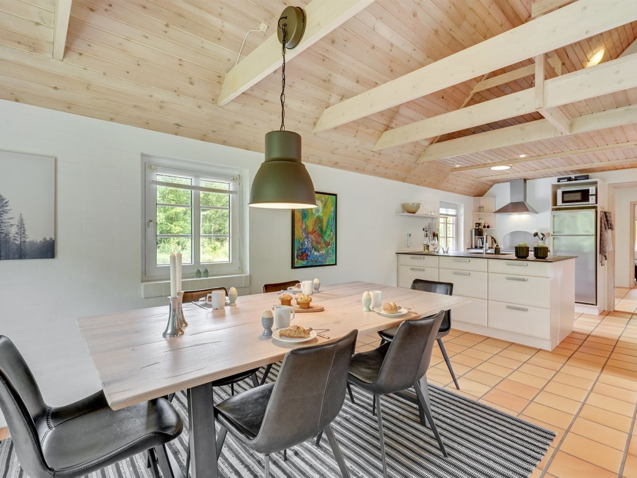 A modern kitchen with white cabinets, a stainless steel refrigerator, and a microwave.