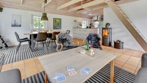A cozy, well-lit room with a dining table, chairs, and a fireplace. - "Osmo" - 900m from the sea by Interhome (Ulfborg)