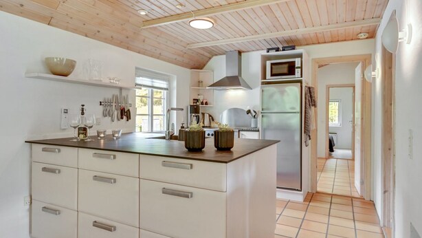 A modern kitchen with a wooden ceiling, white cabinetry, and a central island. - "Osmo" - 900m from the sea by Interhome (Ulfborg)